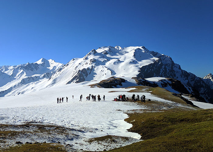A hiker standing on a high mountain peak overlooking a vast alpine landscape